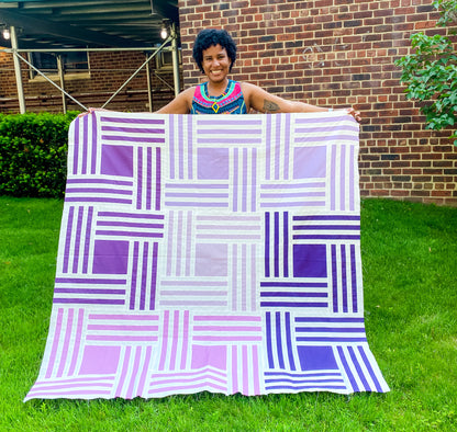 Person holding quilt with white and five different shades of purple.